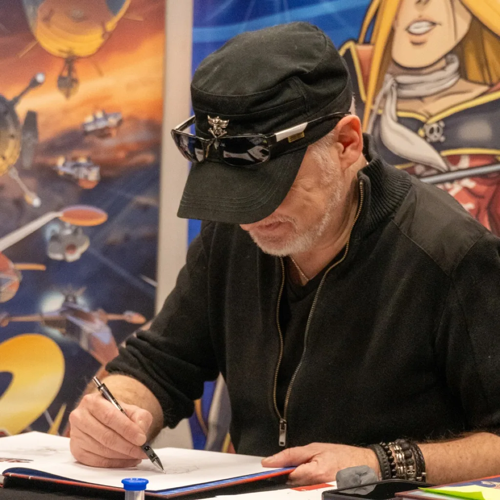 Un auteur dessine en dédicace sur son stand