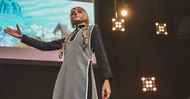 Défilé cosplay sur scène au festival Geek Life, participante en costume médiéval devant un décor animé