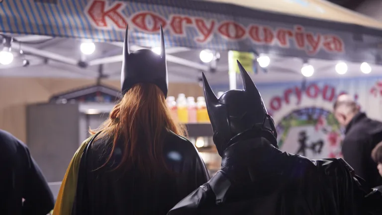 Cosplayers Batman et Batwoman devant un stand japonais au Geek Life Festival